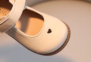 Detailed macro shot of heart pattern cutout on girls beige leather Mary Jane shoes