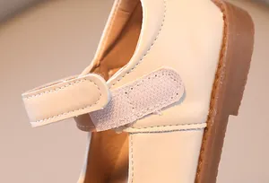 Detailed close-up showing hook-and-loop strap on soft cream leather girl's Mary Jane shoes