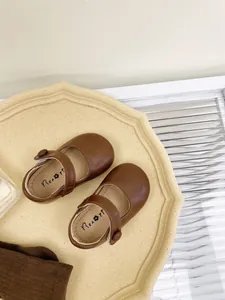 Detailed top view of brown baby Mary Jane leather shoes with soft soles on a tray