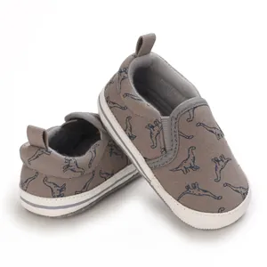 Detailweergave van zachte babyschoenen met blauw dinosauruspatroon op bruin canvas