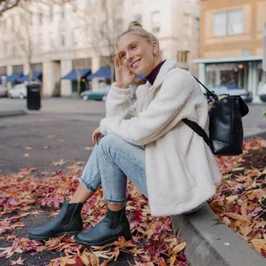 Detalle de botas Martin Chelsea de cuero negro con chaqueta de forro polar blanca