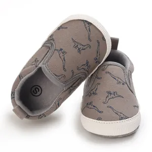 Close-up van grijze baby schoentjes met dinosaurus print en zachte zool, maat S