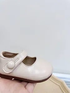 Detailed view of beige faux leather baby Mary Jane shoes with strap and button detail