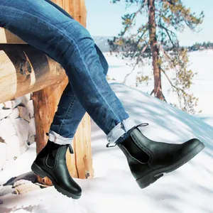 Primer plano de botas Chelsea Martin negras en una escena de invierno con nieve