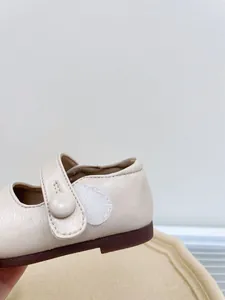 Detail shot of a cream faux leather baby Mary Jane shoe with velcro strap closure.