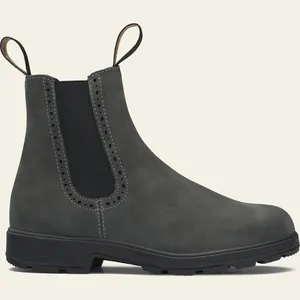 Vista detallada de botines Chelsea de ante gris con perforaciones decorativas estilo brogue.