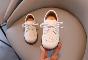 Nahaufnahme weißer Kinderschuhe im britischen Stil mit eleganten Brogue-Details
