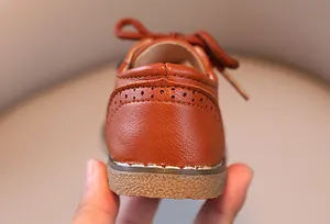 Detaillierte Rückansicht brauner Kinderschuhe im britischen Stil mit elegantem Brogue-Muster