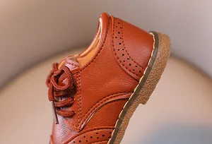 Detail von braunen Lederschuhen für Jungen mit eleganter Brogue-Schnitzerei.