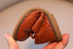 Nahaufnahme der weichen und flexiblen Sohle von braunen Kinderschuhen aus hochwertigem Leder.