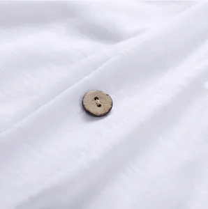 Detailed close-up view of white textured breathable fabric and a brown wooden button