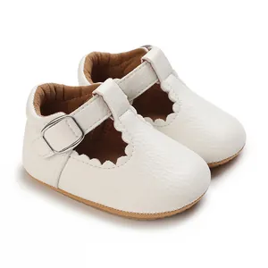 Nahaufnahme weißer Baby-Leder-Schuhe mit Wellenrand und Schnallenriemen