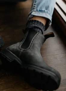 Primer plano de botines Chelsea de cuero gris oscuro para mujer con brogue.