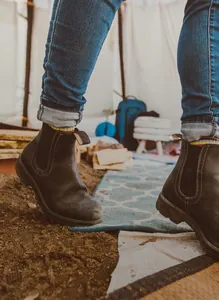 Elegantes botas Chelsea de cuero marrón oscuro para mujer usadas en un campamento al aire libre