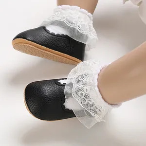 Detail view of black infant princess shoes with white ruffled lace and soft soles.