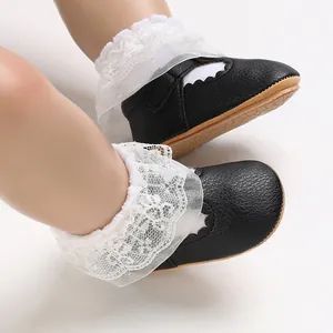 Close-up of black baby princess shoes featuring delicate white lace ruffles and soft soles