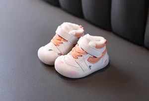 Vue détaillée de chaussures de marche bébé orange et blanc avec doublure en fourrure.