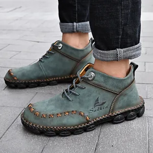 Detail of men's mid-top Martin boots featuring green nubuck leather and handmade stitching