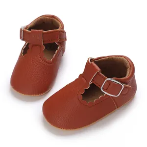 Detailed view of brown baby walking shoes with scalloped edges and T-strap buckle