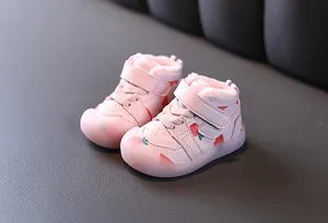 Gros plan sur des chaussures d'hiver roses pour bébé avec motif fraise et doublure polaire