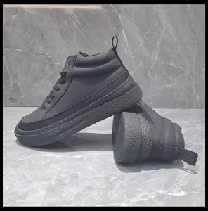 Vue latérale de bottines montantes en cuir noir pour hommes sur un sol en marbre gris