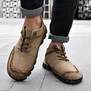 Detailed view of men's brown hand-stitched mid-top casual leather work boots on feet.