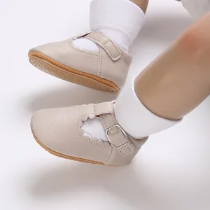 Nahaufnahme von beigen Baby-Mary-Jane-Schuhen mit Muschelrand und Schnallenriemen