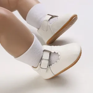 Close-up of white soft sole baby Mary Jane shoes with scalloped edges and buckle strap
