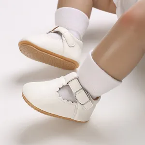 Nahaufnahme von weißen PU-Leder Babyschuhen mit Wellenrand und einer Metallschnalle