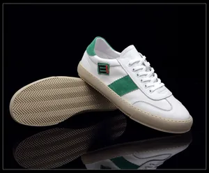 Vue détaillée de baskets en cuir blanc avec daim vert et semelle en gomme beige.