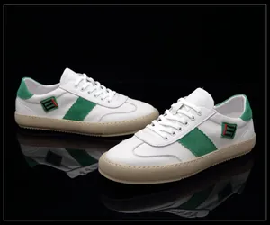 Détail de baskets en cuir blanc avec suède vert et logo à rayures décoratives