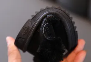 Close-up showing the high flexibility and soft rubber sole of black winter baby snow boots