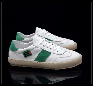 Détail de baskets en cuir blanc avec touches de daim vert et semelles marron.