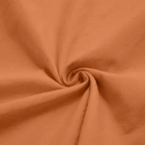 Detailed macro view of soft terracotta orange cotton fabric texture for men's loungewear