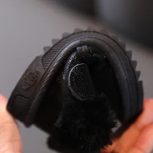 Flexible non-slip sole of warm black baby snow boots with soft fur pom-pom detail