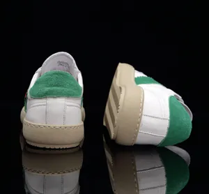 Vue arrière détaillée des baskets en cuir blanc avec talon en daim vert sur fond noir