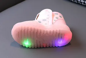 Vista dettagliata della suola a LED rosa su stivali da neve a pois per bambini.