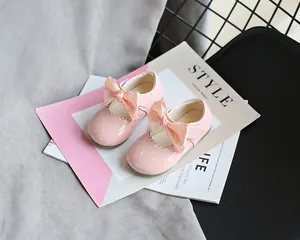 Nahaufnahme von rosa Lacklederschuhen für Mädchen mit großen Satinschleifen auf Magazin