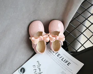 Nahaufnahme rosa Mädchenschuhe aus Lackleder mit dekorativer Schleife und gewellten Kanten