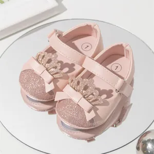 Close-up of pink baby princess shoes with glitter crown and bow decoration