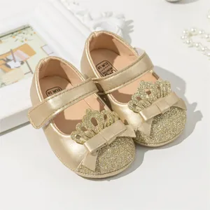 Detailed view of champagne gold baby girl shoes with glitter toes and crown bow