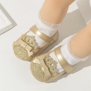 Detailed view of elegant gold glitter baby princess shoes featuring crown and bow