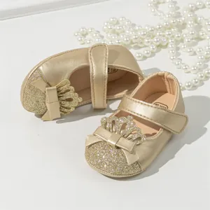 Macro detail of gold glitter baby princess shoes featuring a crown and bow decoration