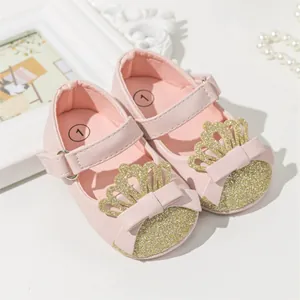Detailed macro shot of pink baby girl princess shoes with a glittery crown and bow decor