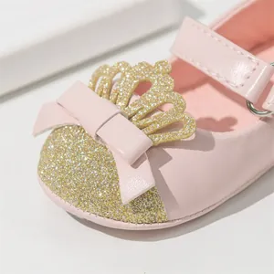 Macro detail of pink baby princess shoe with gold glitter crown and bow decoration