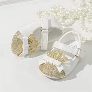 Detailed view of white baby princess shoes with gold glitter toe and crown bow.