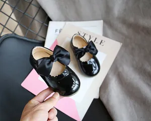 Detailaufnahme schwarzer Mädchen-Mary-Janes aus Lackleder mit großer Satin-Schleife