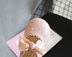 Nahaufnahme eines Mädchenschuhs aus rosa Lackleder mit einer großen Satinschleife