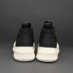 Vista posteriore di sneakers alte in pelle nera da uomo con spesse suole a biscotto crema