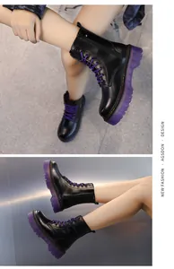 Close-up of black mid-calf Martin boots featuring purple platform soles and laces.